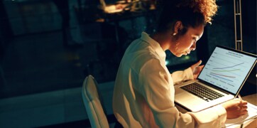 Nainen istuu kannettavan tietokoneen ääressä